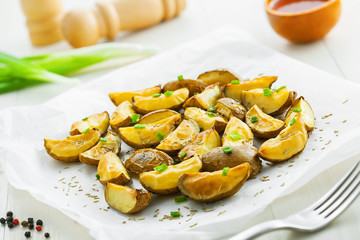 Fresh baked potato wedges with rosemary and spring onion on table