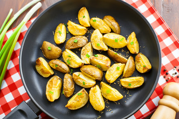 Fresh fried potato wedges with rosemary and spring onion on table, top view, close-up
