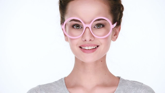 Young  beautiful  smiling woman in  glasses pink color   posing at camera  on white background. Closeup view.