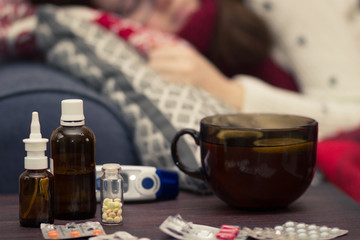 sick woman sleeping in bed next to pills and drugs