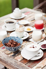 Perfrect healthy breakfast on patio in summer day. Fried eggs, cappuccino, fruits and muesli. Yummy and delicious
