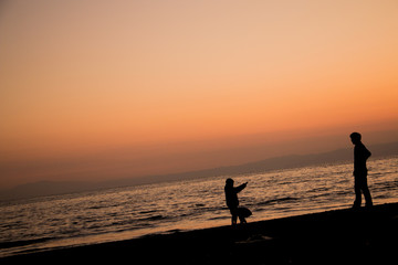 夕焼けの浜辺で遊ぶ親子