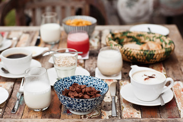 Perfrect healthy breakfast on patio in summer day. Fried eggs, cappuccino, fruits and muesli. Yummy and delicious