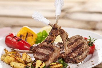 Lamm gegrillt auf wei&szlig;em Teller die Knochen in Papiermanschetten gesteckt