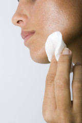 application de crème sur des bouton du visage femme
