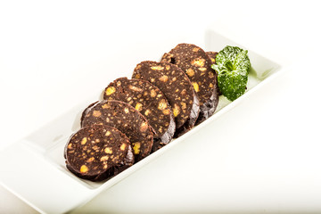Chocolate sweet roll slices with mint leaves in sugar on white plate closeup