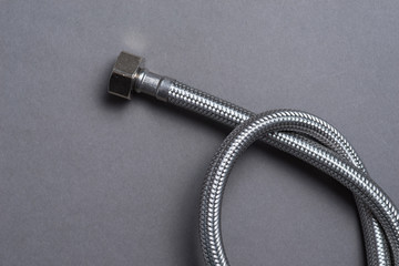 Braided stainless steel water hose over grey background