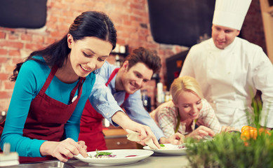 happy friends and male chef cooking in kitchen