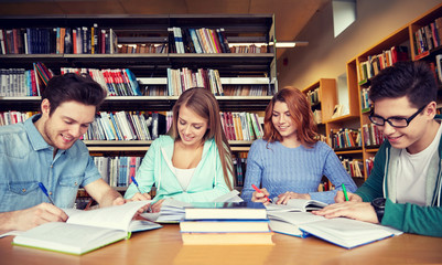 happy students writing to notebooks in library