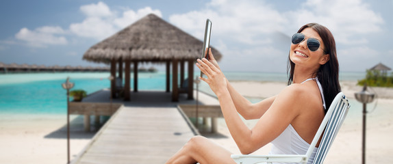 smiling woman with tablet pc sunbathing on beach