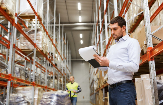 businessman writing to clipboard at warehouse