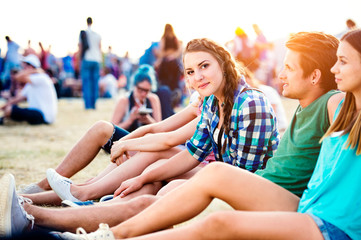 Teenagers at summer music festival, sitting on the ground