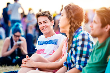 Obraz na płótnie Canvas Teenagers at summer music festival, sitting on the ground