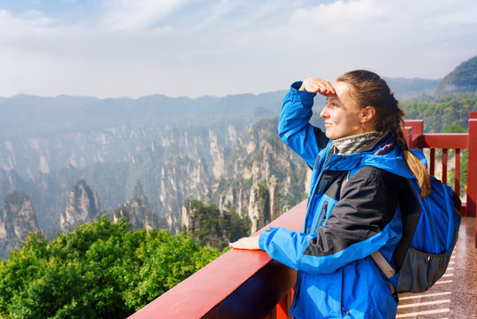 Young smiling female tourist enjoying amazing mountain view