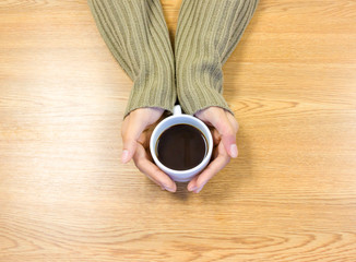 Female hands holding cups of coffee on wooden table background