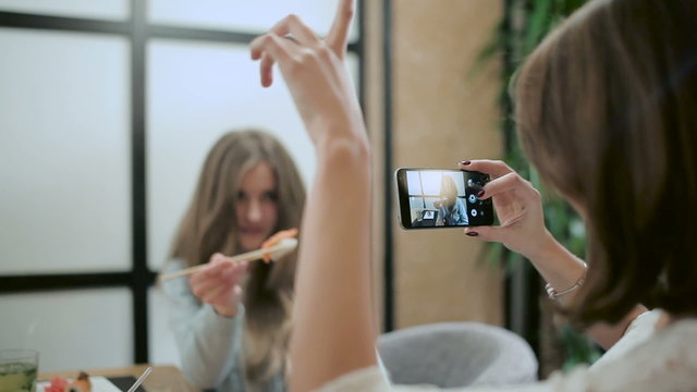 Girl photographing her friend in the restaurant