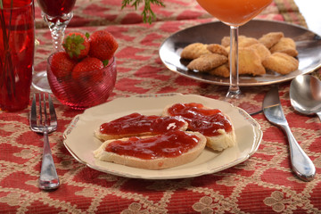 Pan tostado con mermelada de fresas y bizcochos.