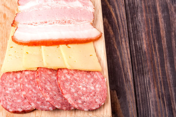 cheese, bacon and salami on a cutting board