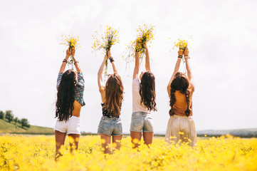 four beautiful hippie girl in a field of yellow flowers