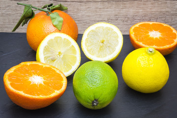 Fototapeta na wymiar several mature citrus fruit on a tray slate - lemon, lime and tangerine 
