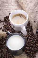 White and black cup of coffee and coffee beans