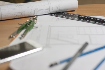 Architectural blueprints and blueprint rolls and a drawing instruments on architects desk