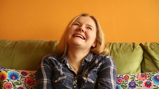 Woman laughing on the couch at home 
