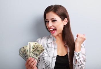 Happy young casual woman holding dollars and showing yes success