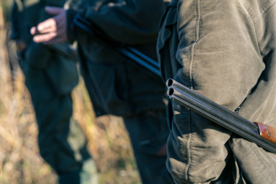 Detail of hunters holding theirs rifles.