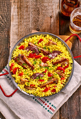 Paella Dish and Beer on Rustic Wooden Table