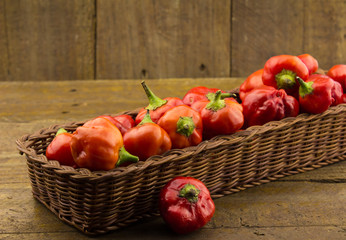 Fototapeta na wymiar Rustic basket of red chilli peppers on rough wood background