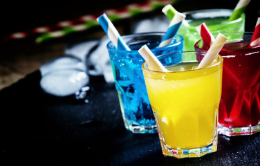 Colorful cocktails with straws on a dark background, selective f