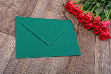 Green envelope and roses on a wooden background