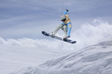 Snowboarder making jump, extreme mountain freeride.