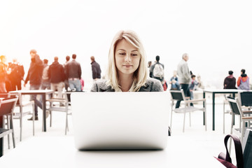 young attractive girl with blonde hair working with a laptop computer outside. Beautiful businesswoman searching information on the Internet