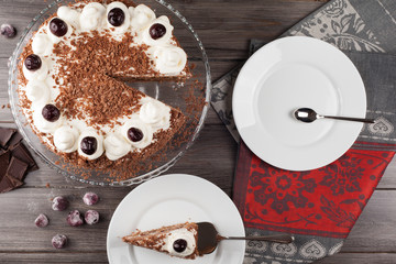 Black forest cake decorated with whipped cream and cherries. 