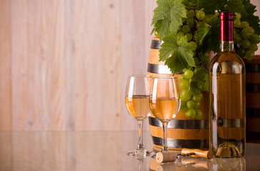 Glasses of wine with a bottle a barrel and grapes