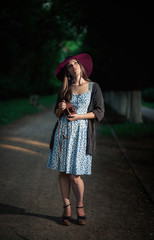 pretty slim girl with long hair in an elegant hat in a simple flowered dress in warm jacket with a...