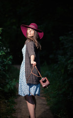 pretty slim girl with long hair in an elegant hat in a simple flowered dress in warm jacket with a...