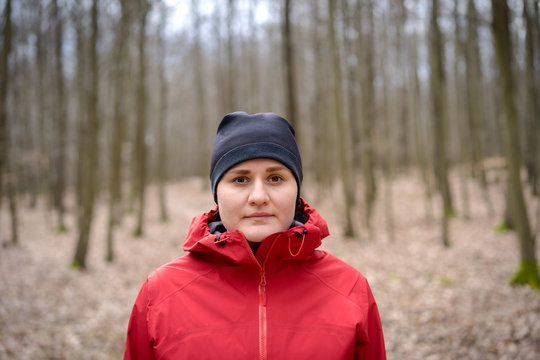 Portrait of young woman standing in middle of a forrest. Looking to camera.
