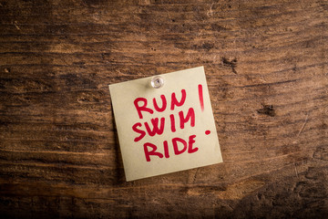 run swim ride! - motivation paper note on wood noticeboard