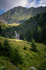 Fototapeta na wymiar Beautiful waterfall in the scenery of green mountains in Romania