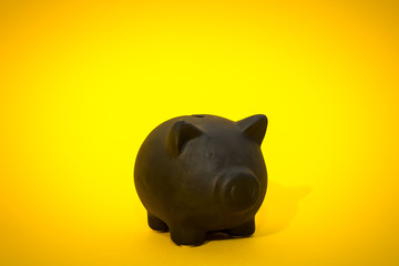 Black piggy bank on the yellow background, the symbol of saving for a rainy day