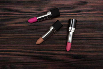 three lipsticks on a wooden background