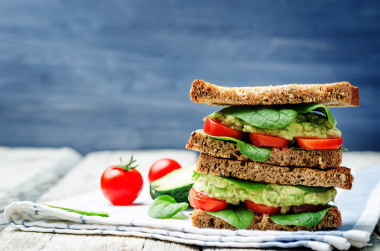 Smashed avocado spinach tomato grilled rye sandwich