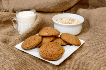 Oatmeal cookies with milk and oatmeal flakes on burlap