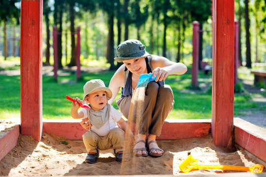 Mom plays with the child in a sandbox