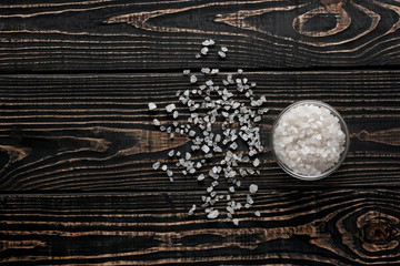 white crystals of salt in a glass bowl  on black wood  backgroun