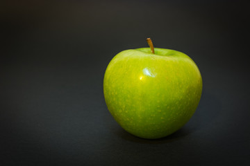 Green apple on the black background