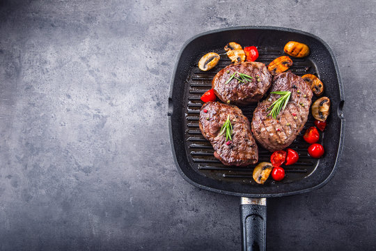 Grill beef steak. Portions thick beef juicy sirloin steaks on grill teflon pan or old wooden board.
